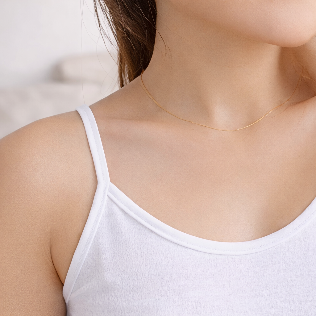 Close-up of white camisole neckline and strap showing soft fabric texture and smooth finish